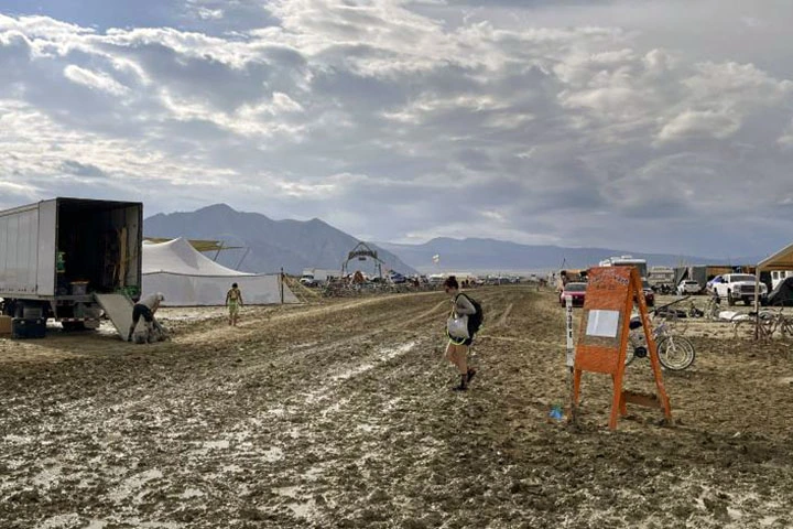 Foto ampla de uma pessoa andando sobre a lama no festival Burning Man