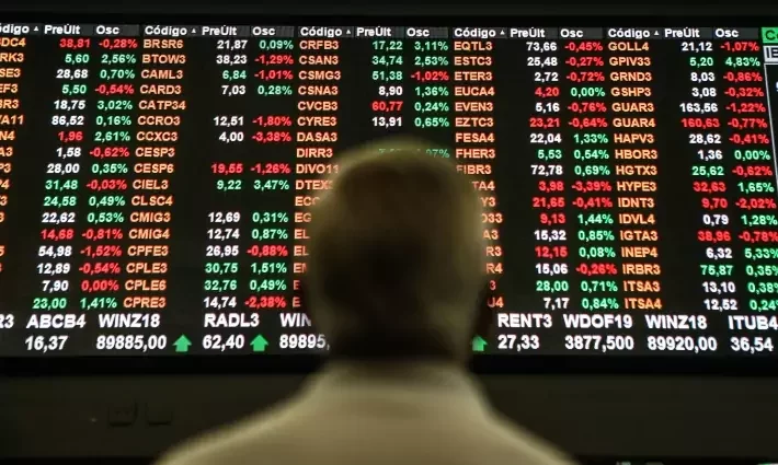 Foto de um homem de costas olhando para marcadores da bolsa de valores