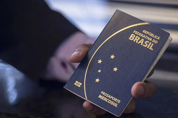 Foto de uma mão segurando um passaporte brasileiro