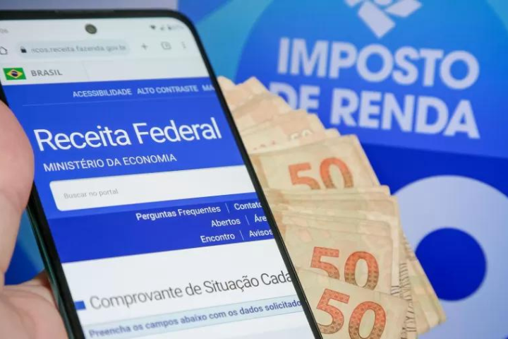 Smartphone com o site da receita federal e notas de R$ 50 ao fundo