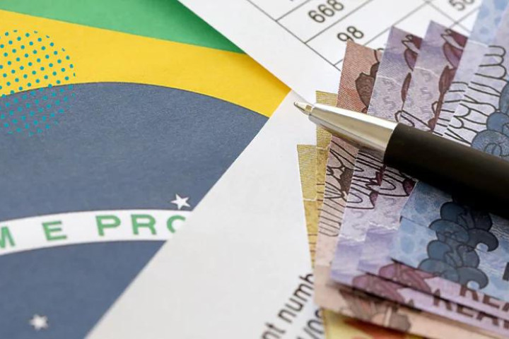 Foto de notas de dinheiro Real sobre a bandeira do Brasil, ilustrando a Reforma Tributária